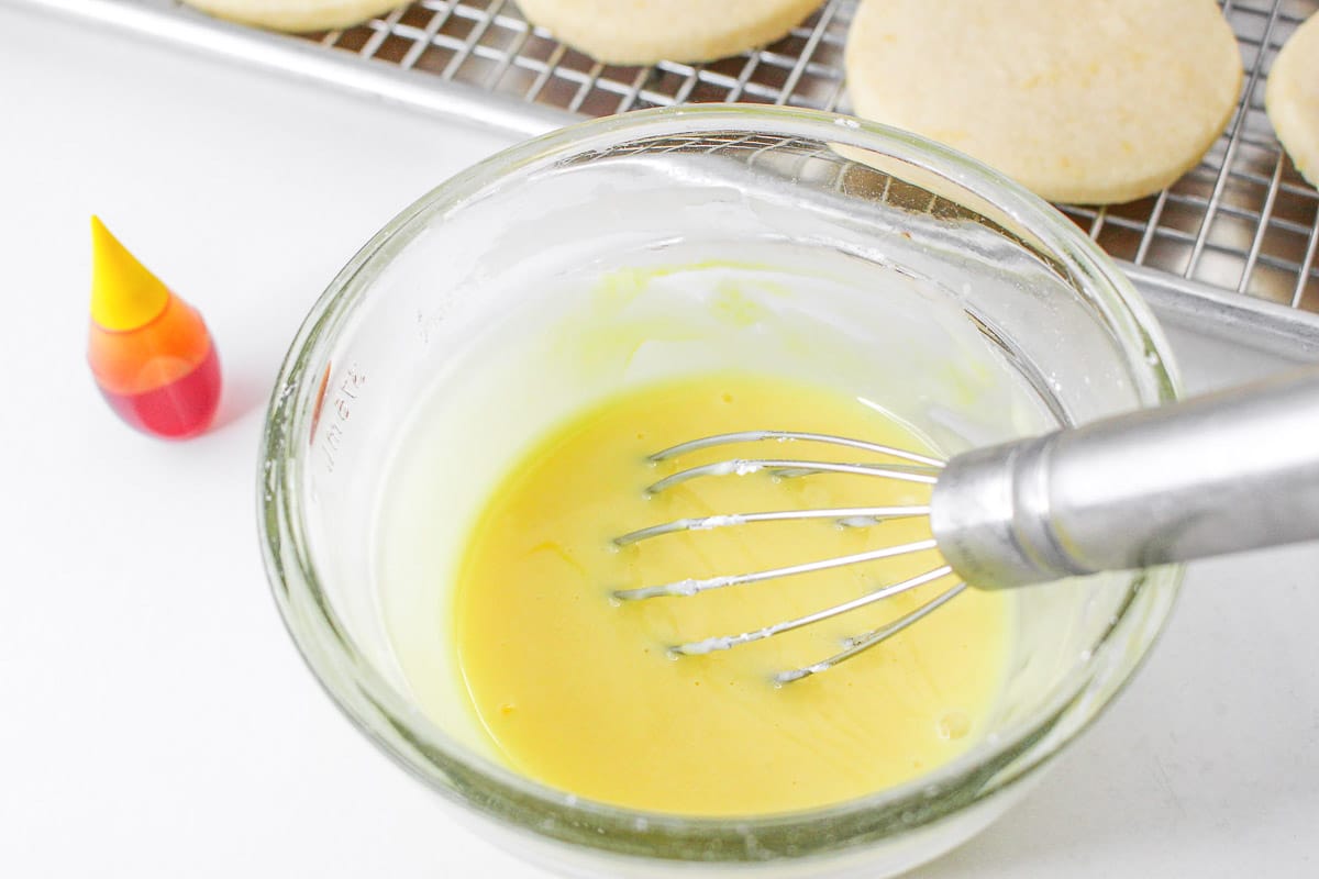 Lemon glaze being whisked in mixing bowl.