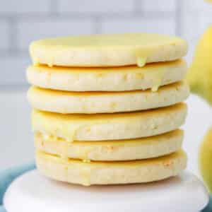 Stack of six lemon shortbread cookies on white cookie stand.