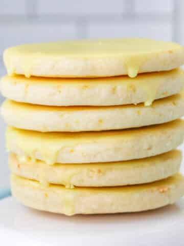 Stack of six lemon shortbread cookies on white cookie stand.