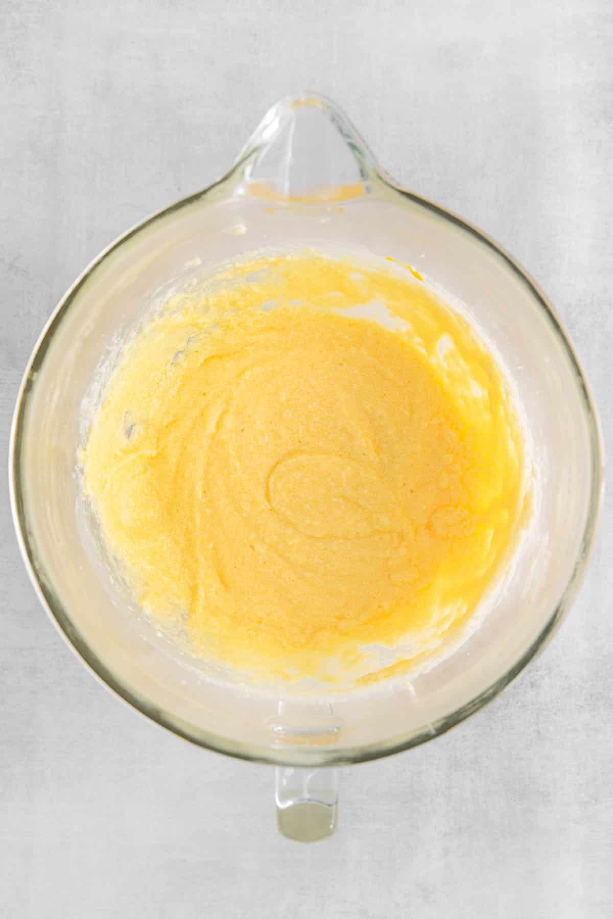 Eggs and vanilla added to butter and sugar mixture in a glass bowl.