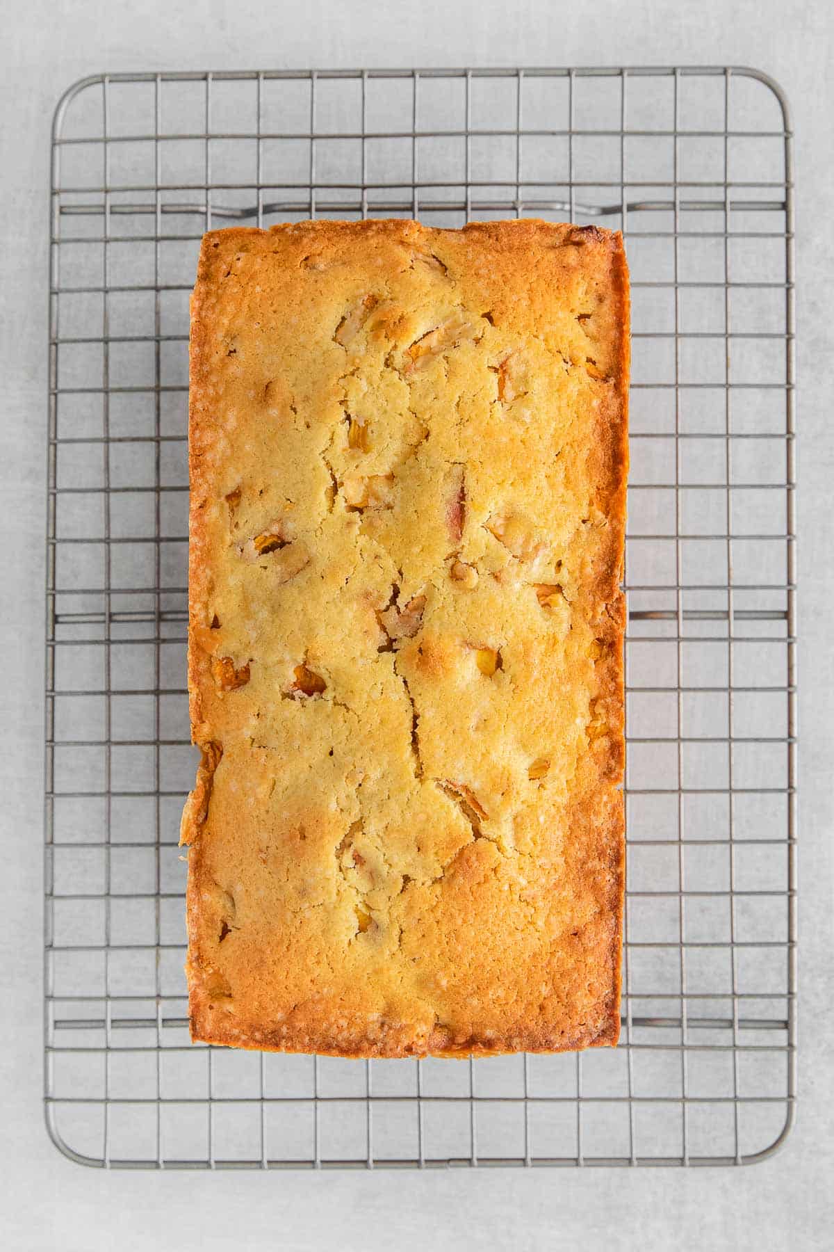 Loaf of peach cobbler pound cake on a wire cooling rack.