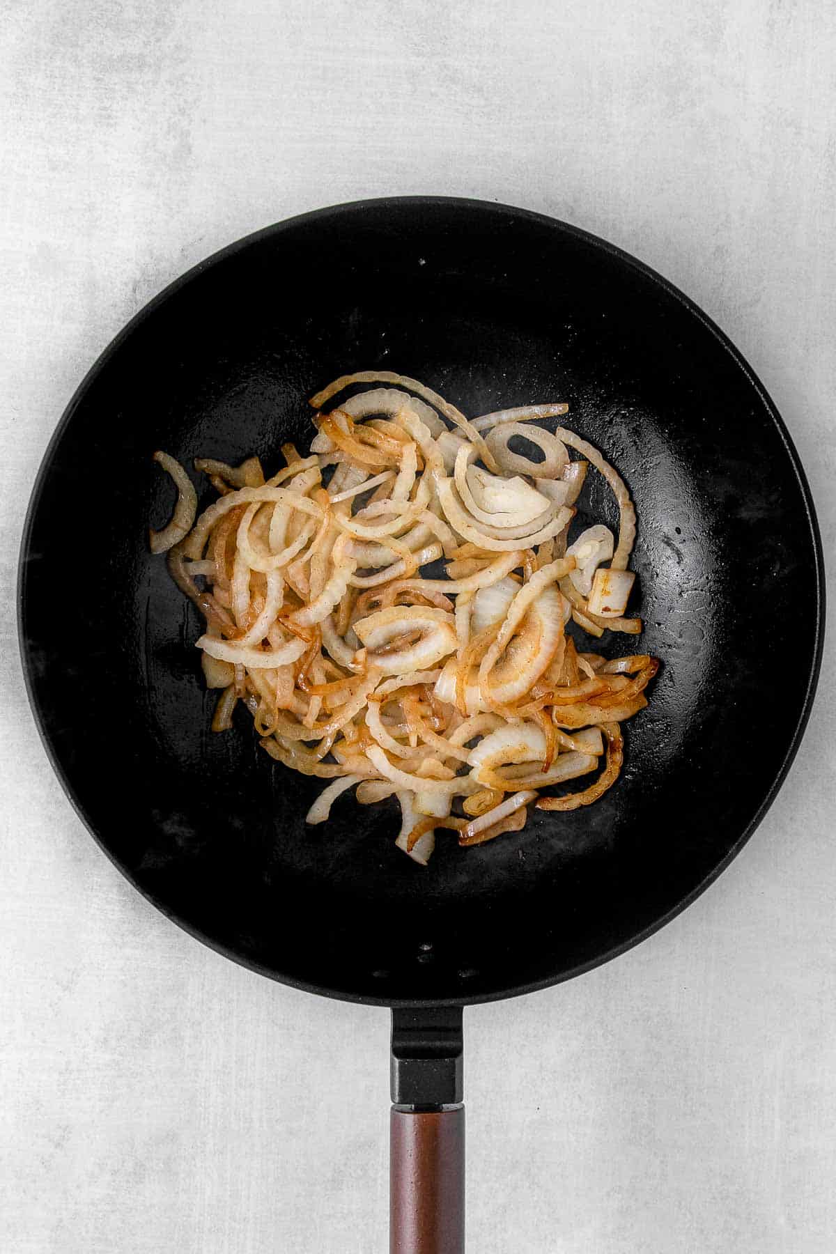 Cooking sliced onion in large pan.