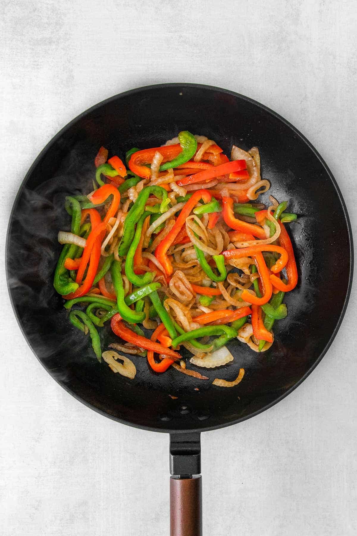 Sliced onion and sliced bell peppers in skillet.