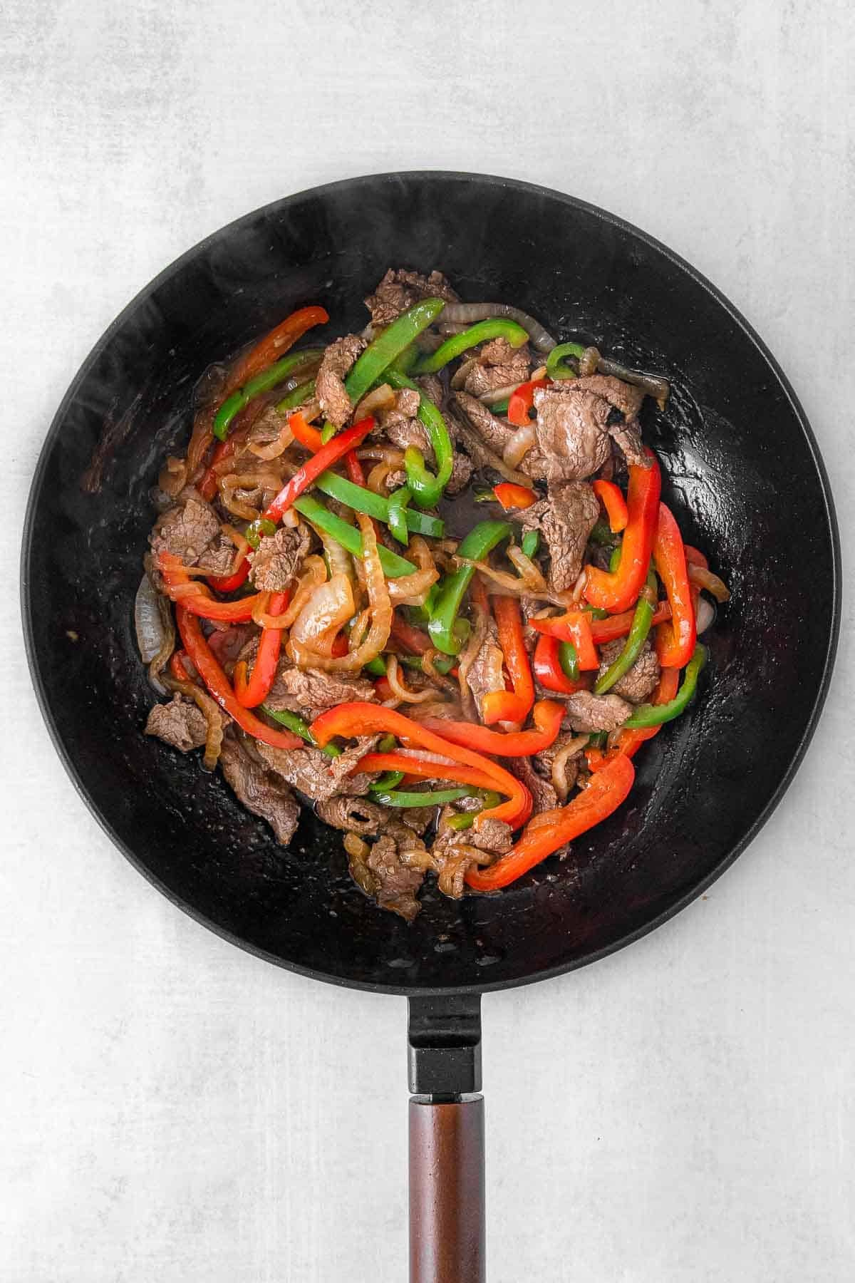 Skillet with steak, onion and bell peppers.