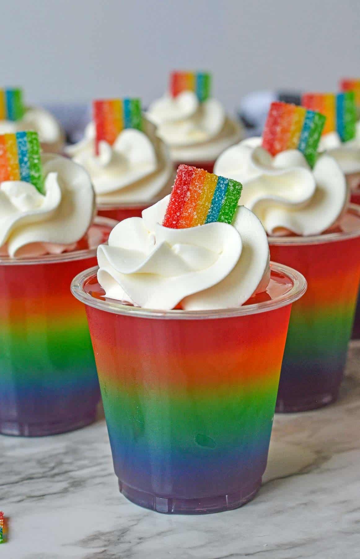 Several rainbow jello shots topped with cool whip and small airhead xtreme pieces.
