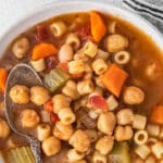 vegetarian minestrone soup with chickpeas and vegetables in a white bowl.
