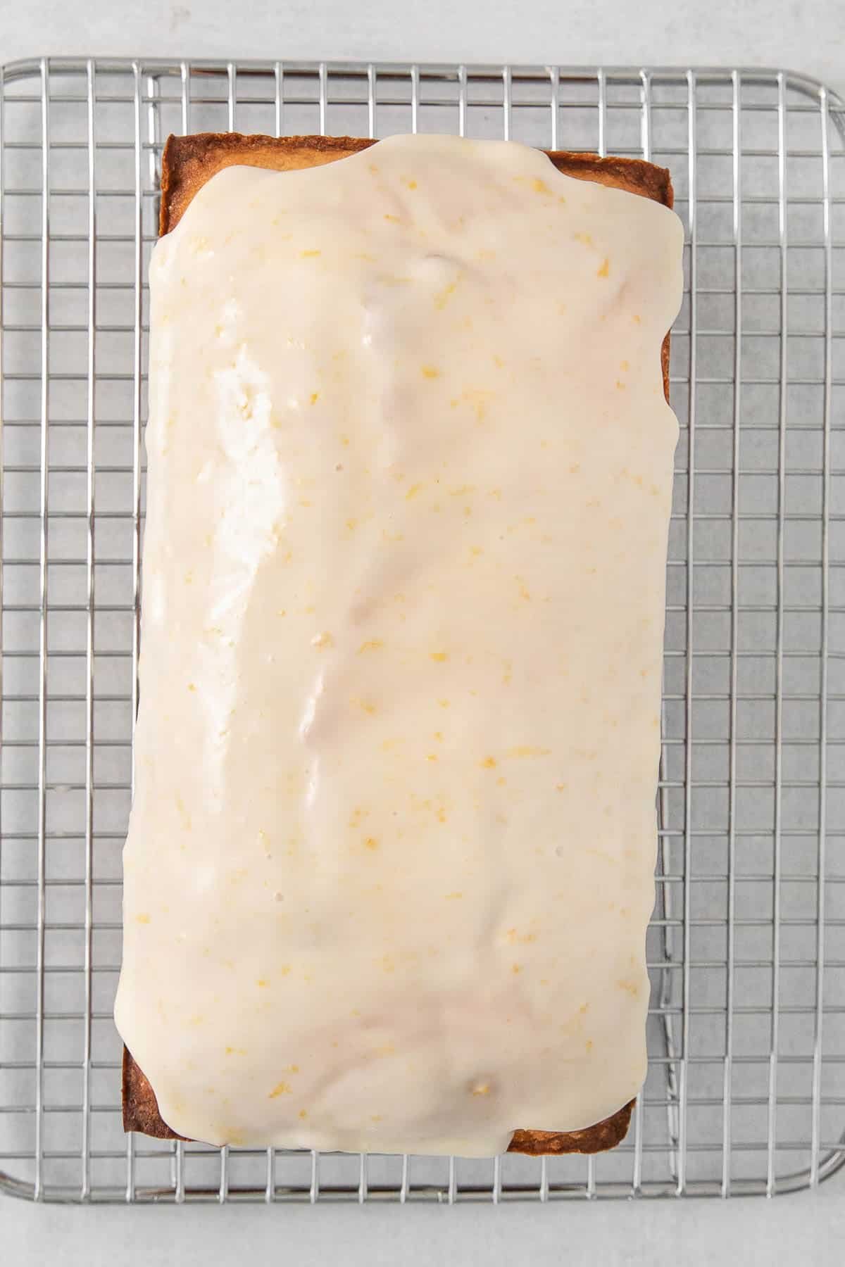 Lemon pound cake topped with lemon glaze on a wire cooling rack.