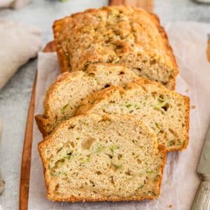 3 slices of zucchini bread on bread board.