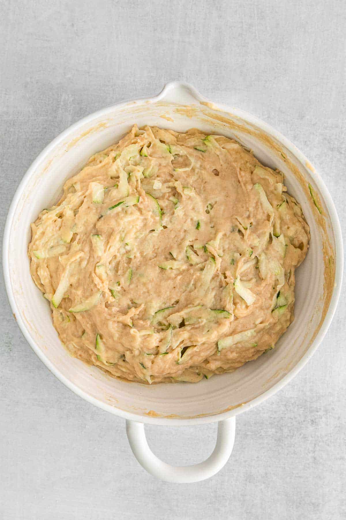 Zucchini bread batter in white mixing bowl.