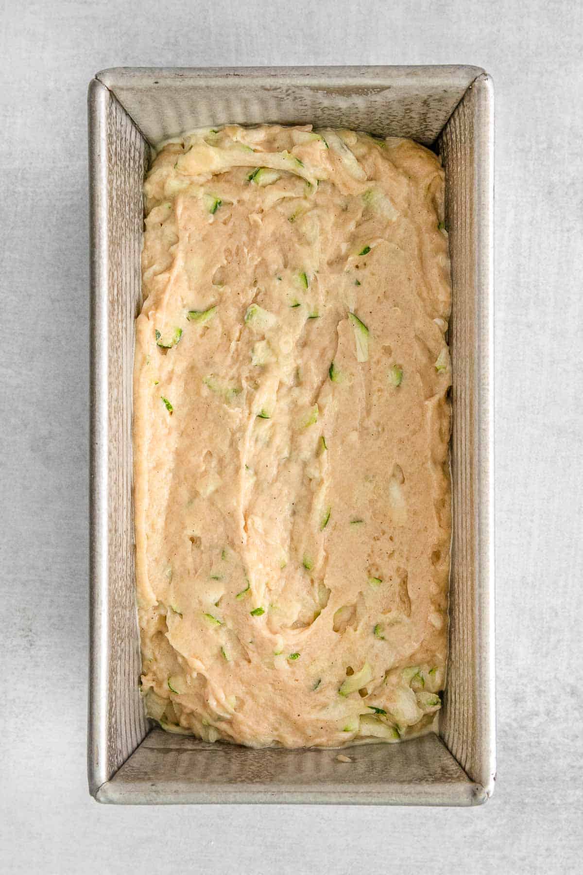 Zucchini bread batter evenly spread in loaf pan.
