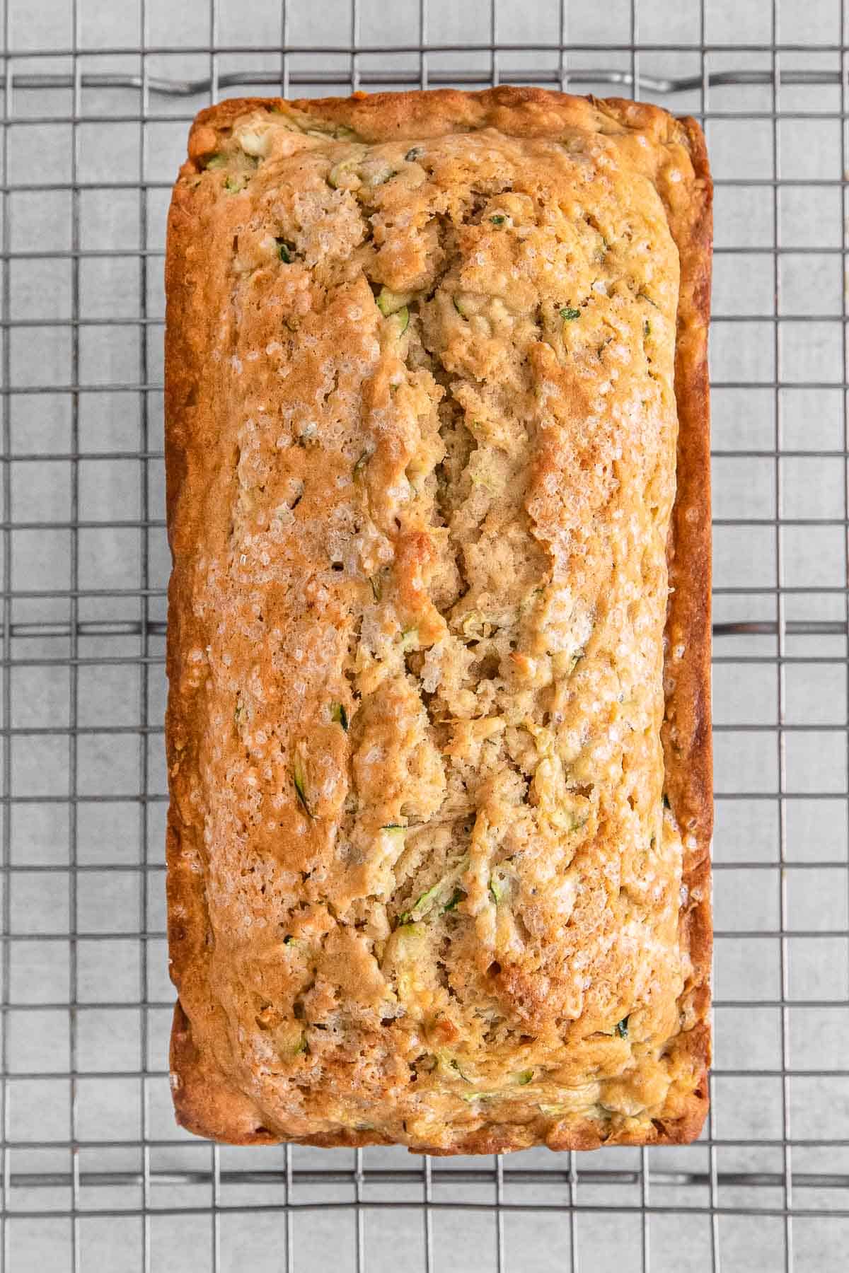 Baked zucchini bread on metal wire tray.
