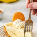 Silver fork inserted into a piece of banana pudding pie on white plate.