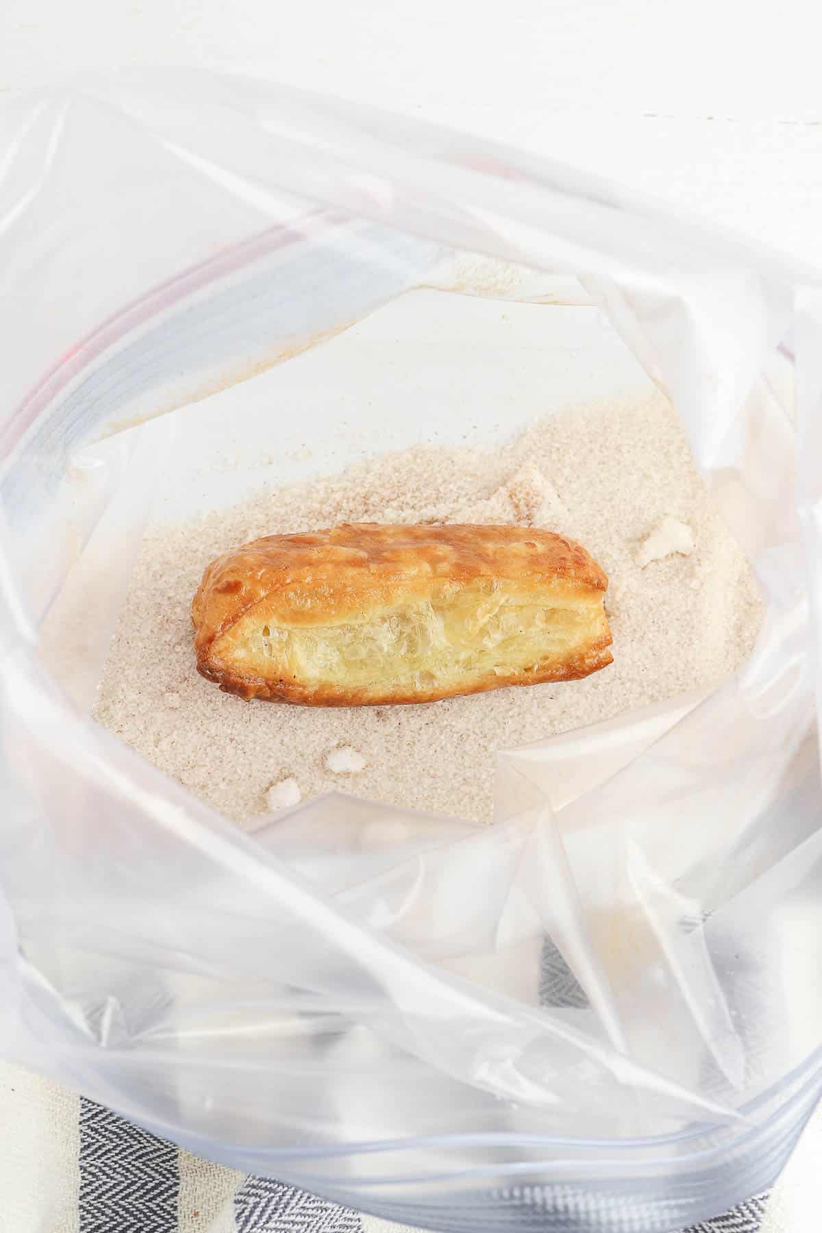 plastic baggie of cinnamon sugar mixture with a churro inside.