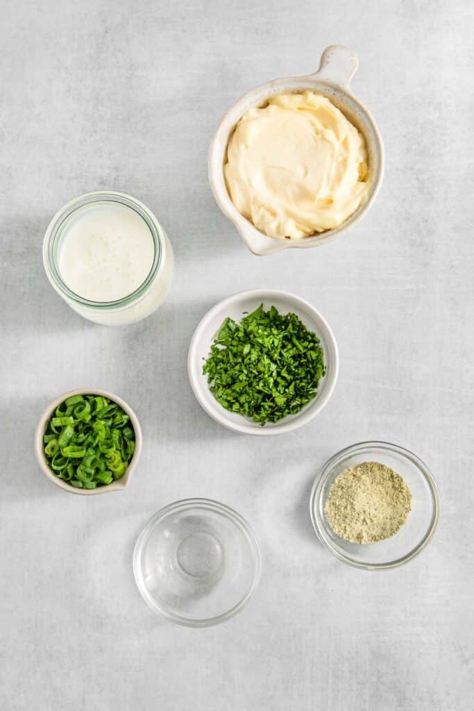 Several bowls of ingredients for BLT pasta salad dressing - mayonnaise, buttermilk, green onions, ranch dressing mix, parsley, white wine vinegar.