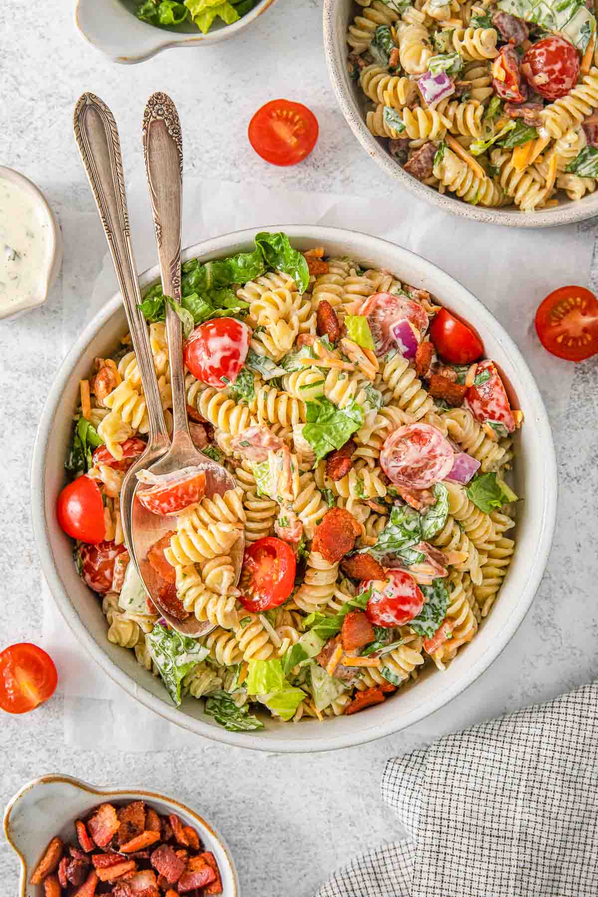 BLT pasta salad with two spoons in a white bowl.