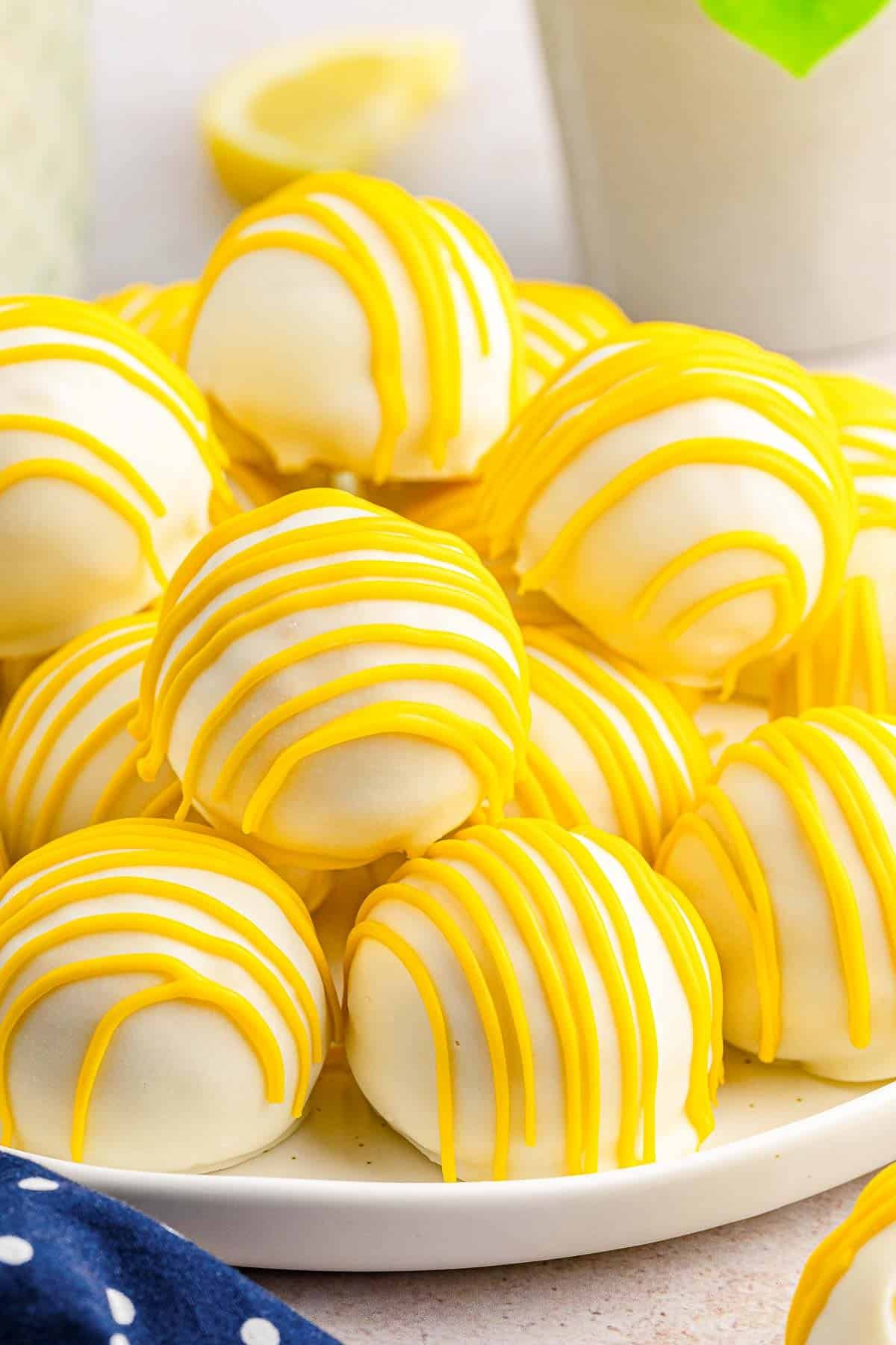 Several lemon cake balls stacked on a white plate.