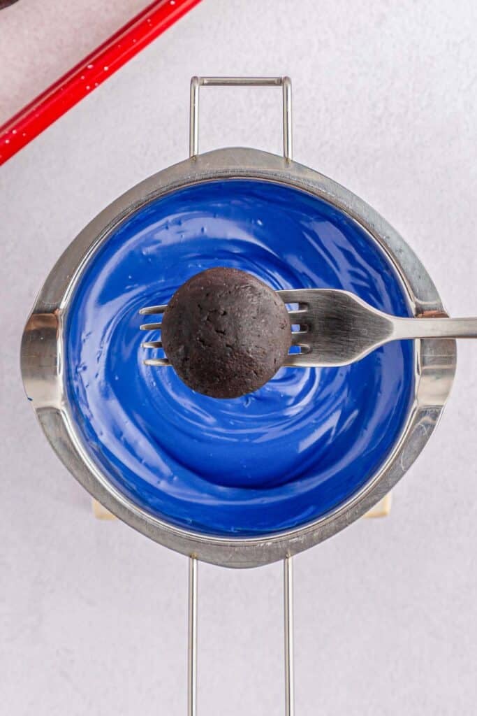 Oreo ball being dipped into blue candy melt.