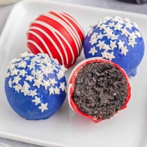 4 red and blue coated oreo balls on a white plate.