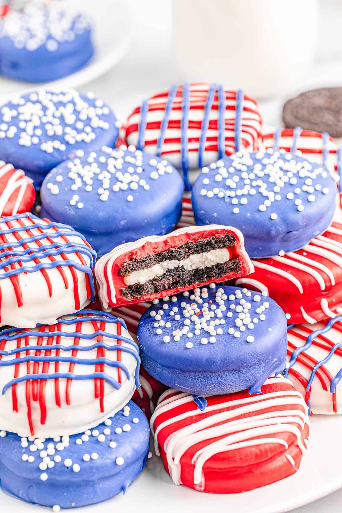 Pile of patriotic oreos with one with a bite taken on a white plate.