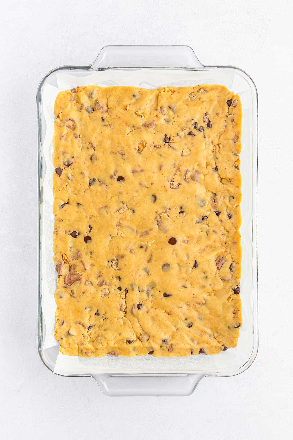 glass baking dish with cookie dough pressed down in it.