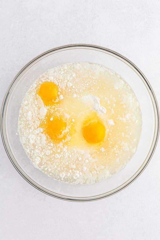 glass mixing bowl with three raw eggs in cake mix. 