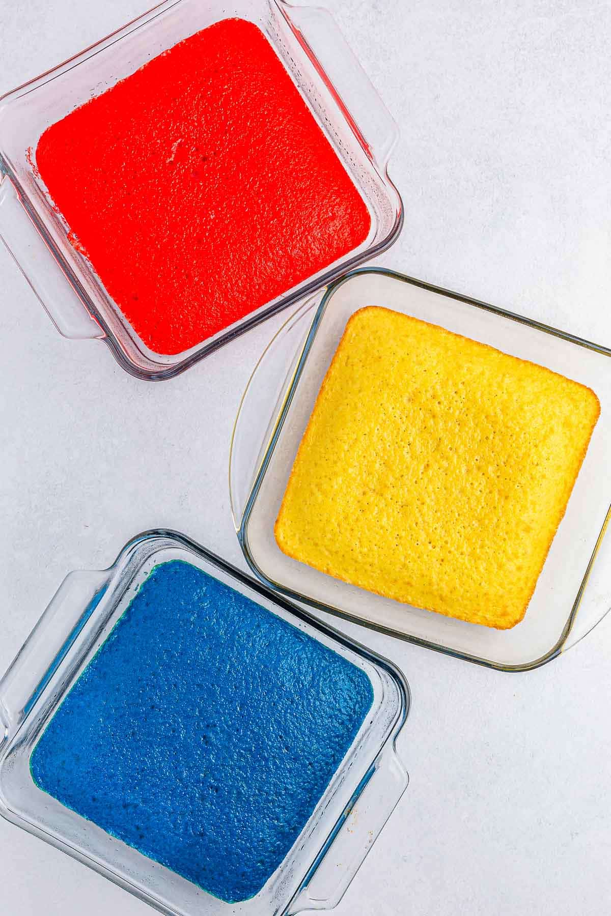 three square glass baking dishes. one blue, one red and one white.