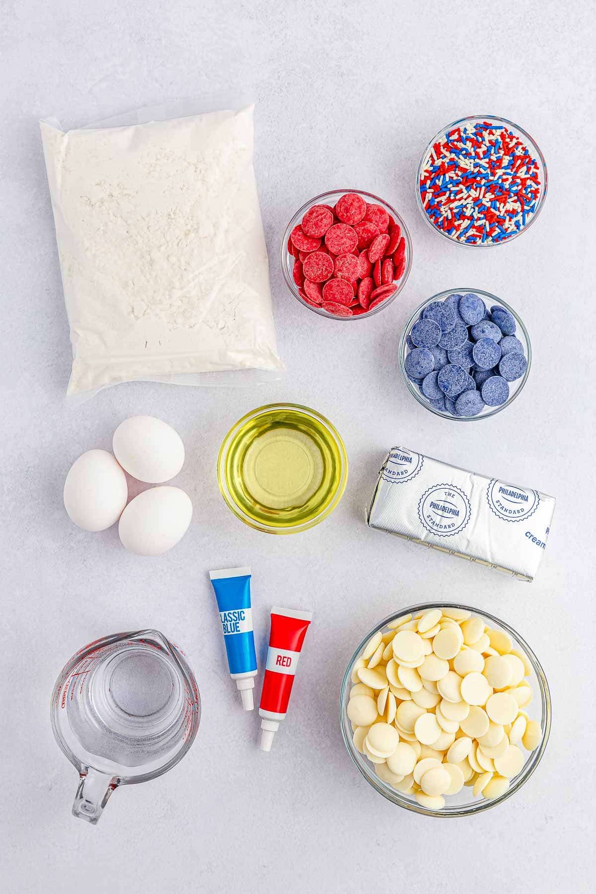 ingredients for red white and blue cake balls - white cake mix, 3 eggs, oil, cream cheese, and red white and blue candy melting wafers.