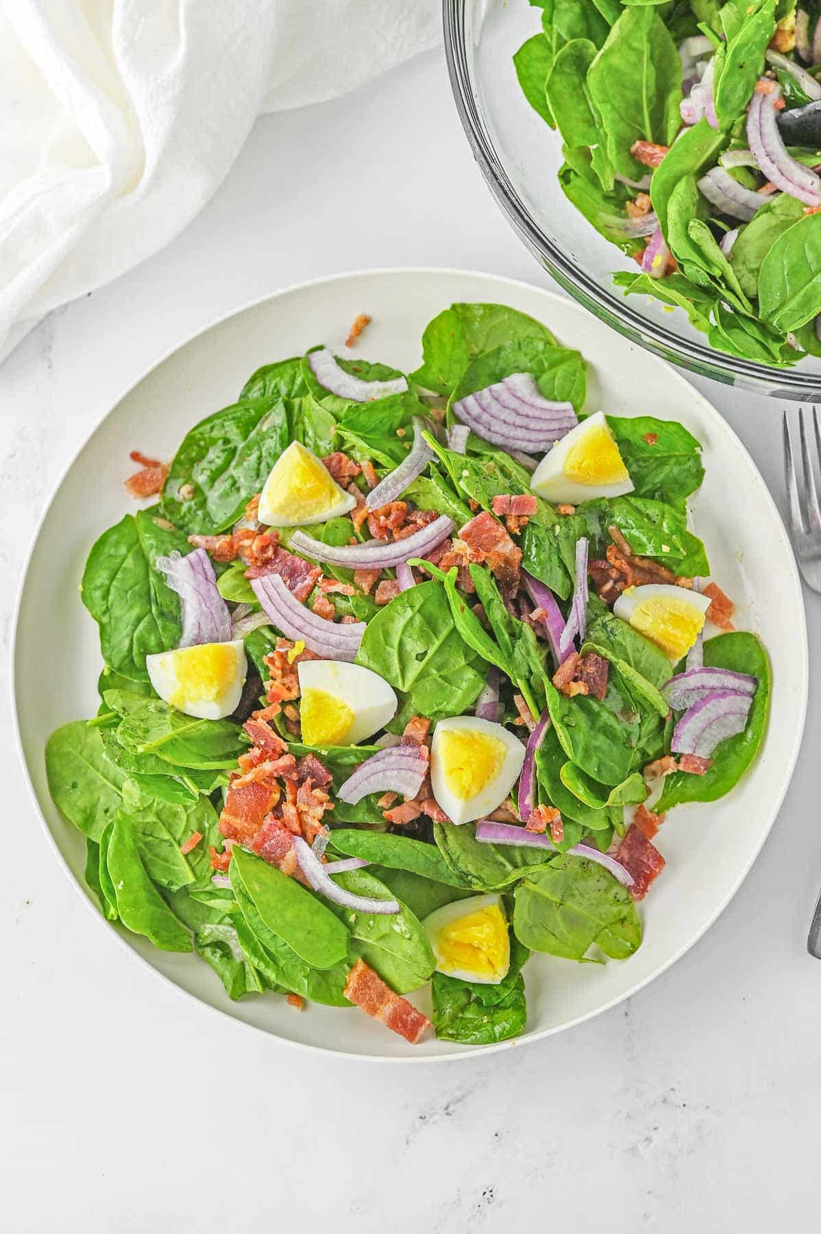 Spinach salad in a white bowl.