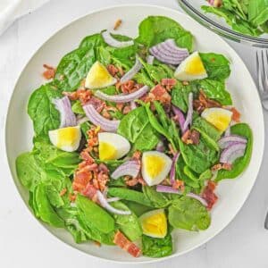 Spinach salad in a white bowl.