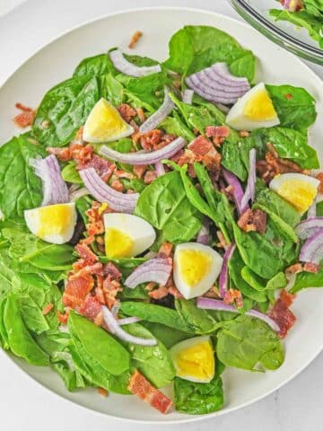 Spinach salad in a white bowl.