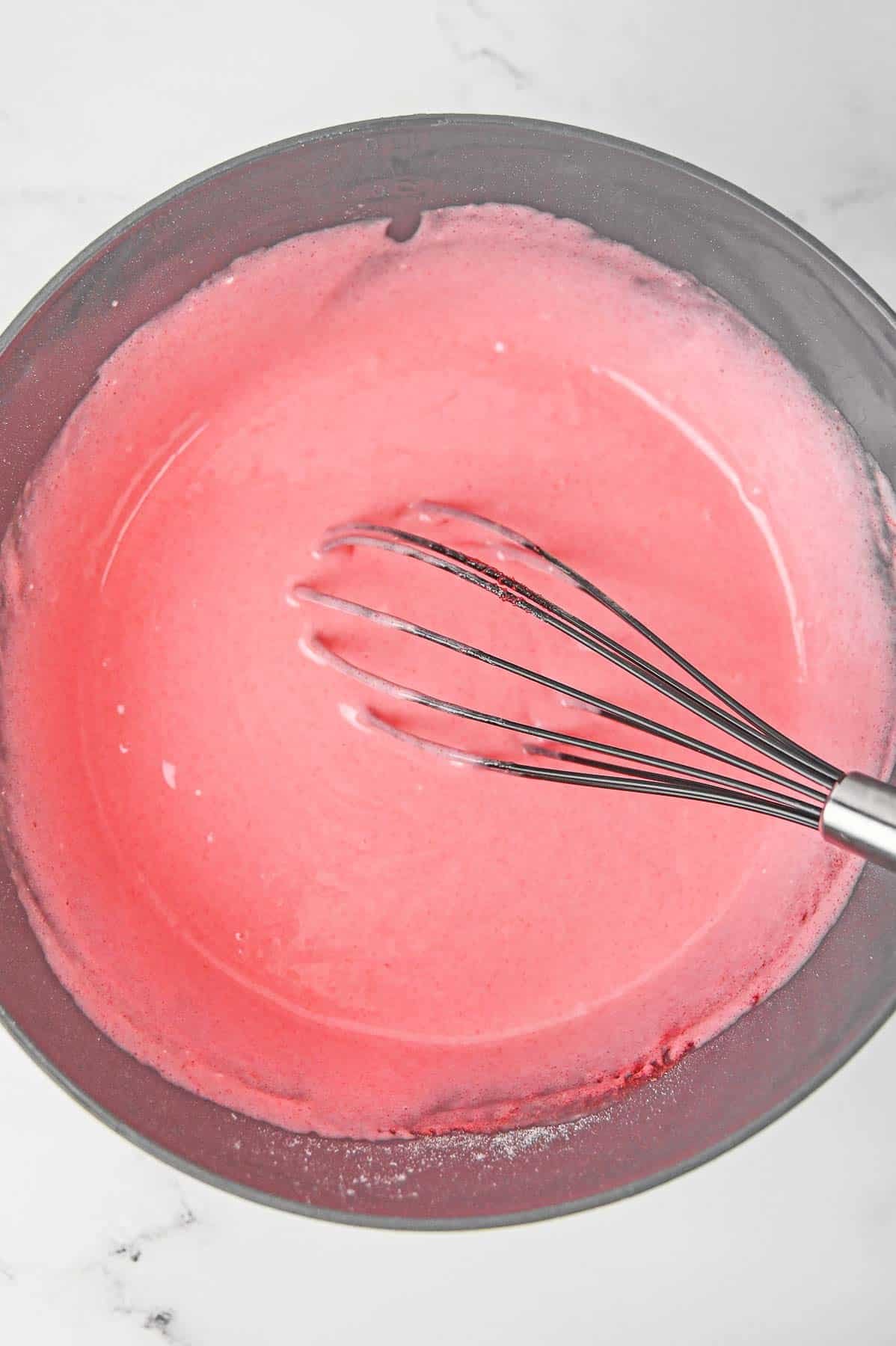 Strawberry jello added to cake mix in large mixing bowl.