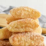 stack of several air fryer churros with cinnamon sugar coating on a white plate.