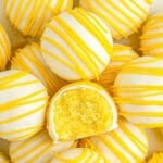 lemon cake balls stacked on a white plate with one with a bite taken out of it.