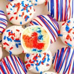 closeup of patriotic cake balls with red white and blue sprinkles and red and blue drizzle.