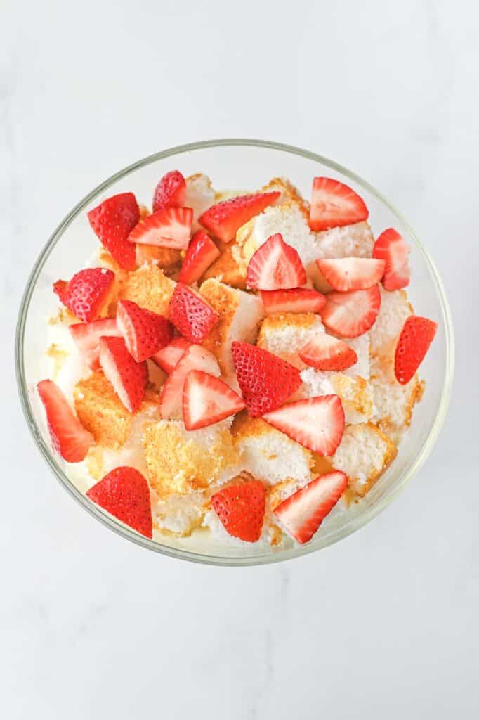 strawberries and angel food cake in a trifle dish.