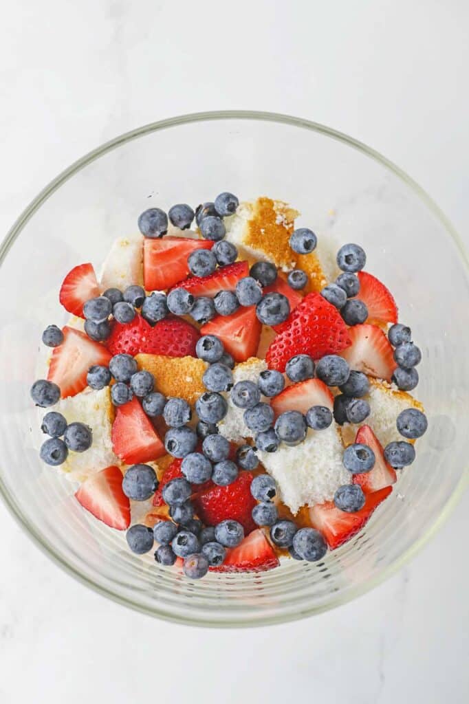 blueberries and strawberries added to a trifle bowl.