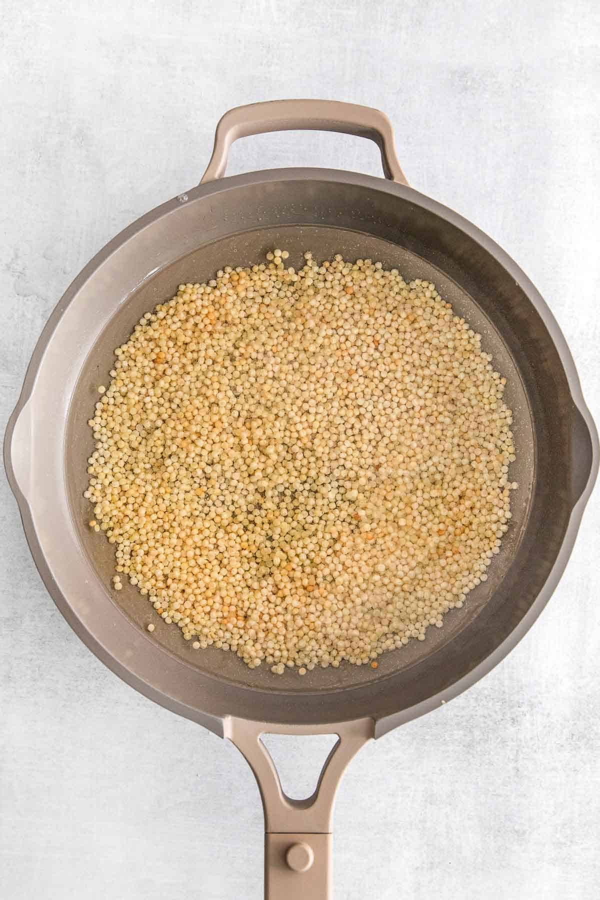 Couscous cooking in a large skillet.