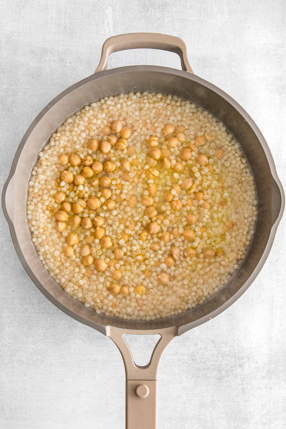 Chic peas and couscous cooking in a large skillet.