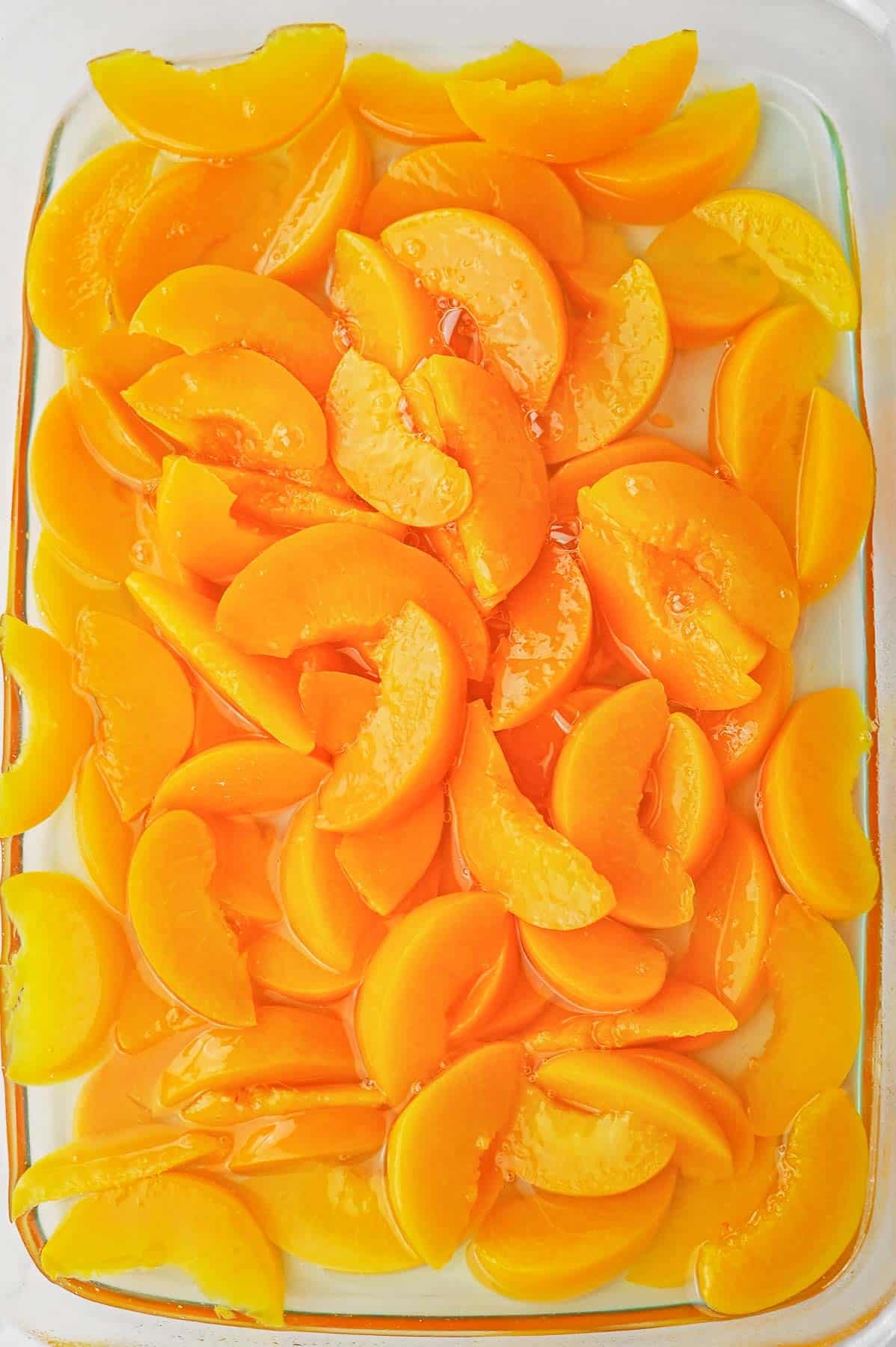 Peaches spread in glass baking dish.