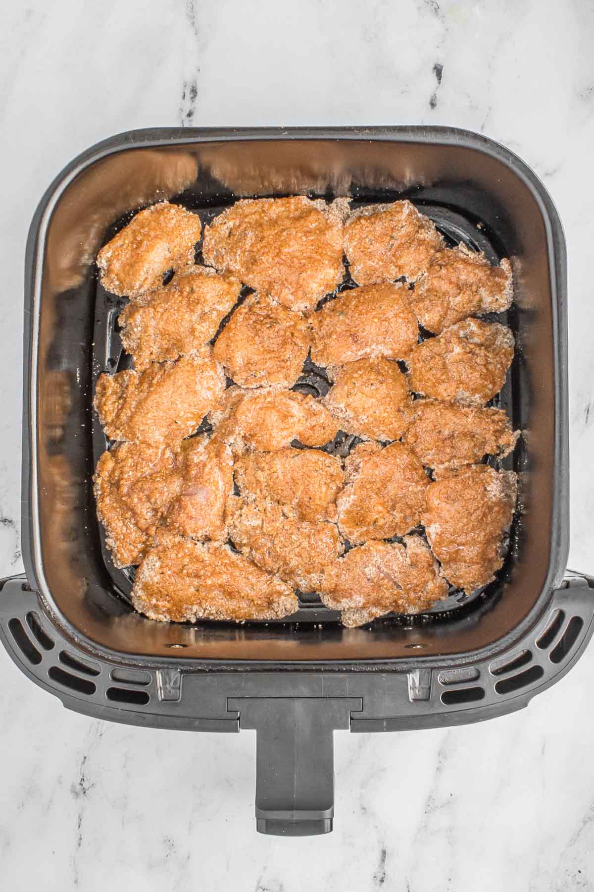 Coated chicken nuggets in air fryer.