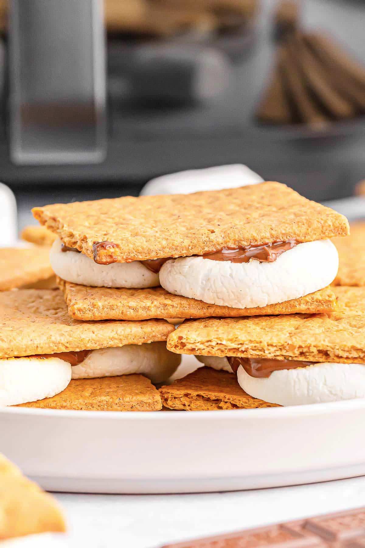 Stack of several smores stacked on a large white plate.