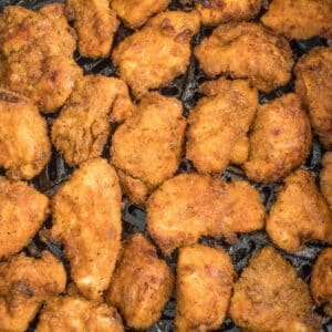 several crispy chicken nuggets in bottom of air fryer basket.