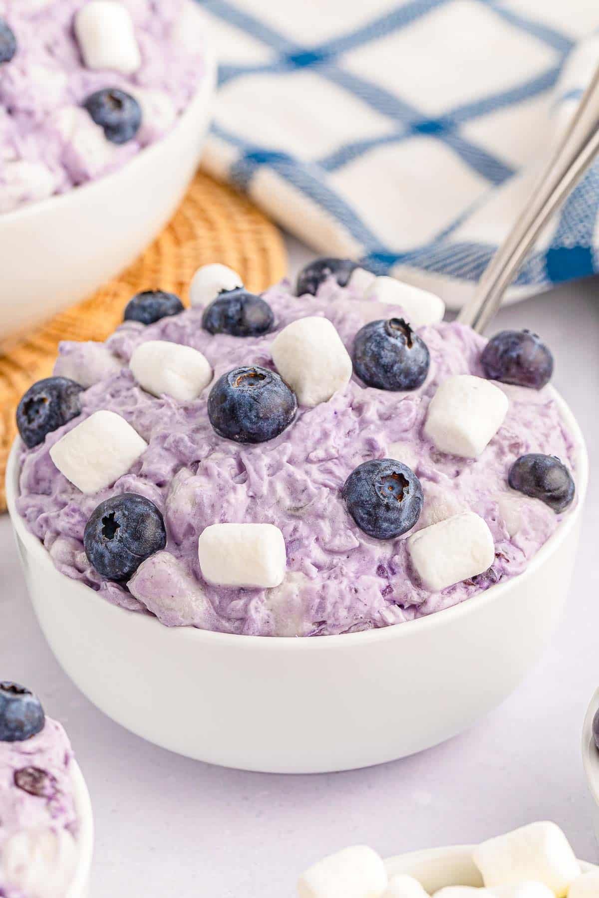 Blueberry fluff topped with mini marshmallows and blueberries in a white bowl.