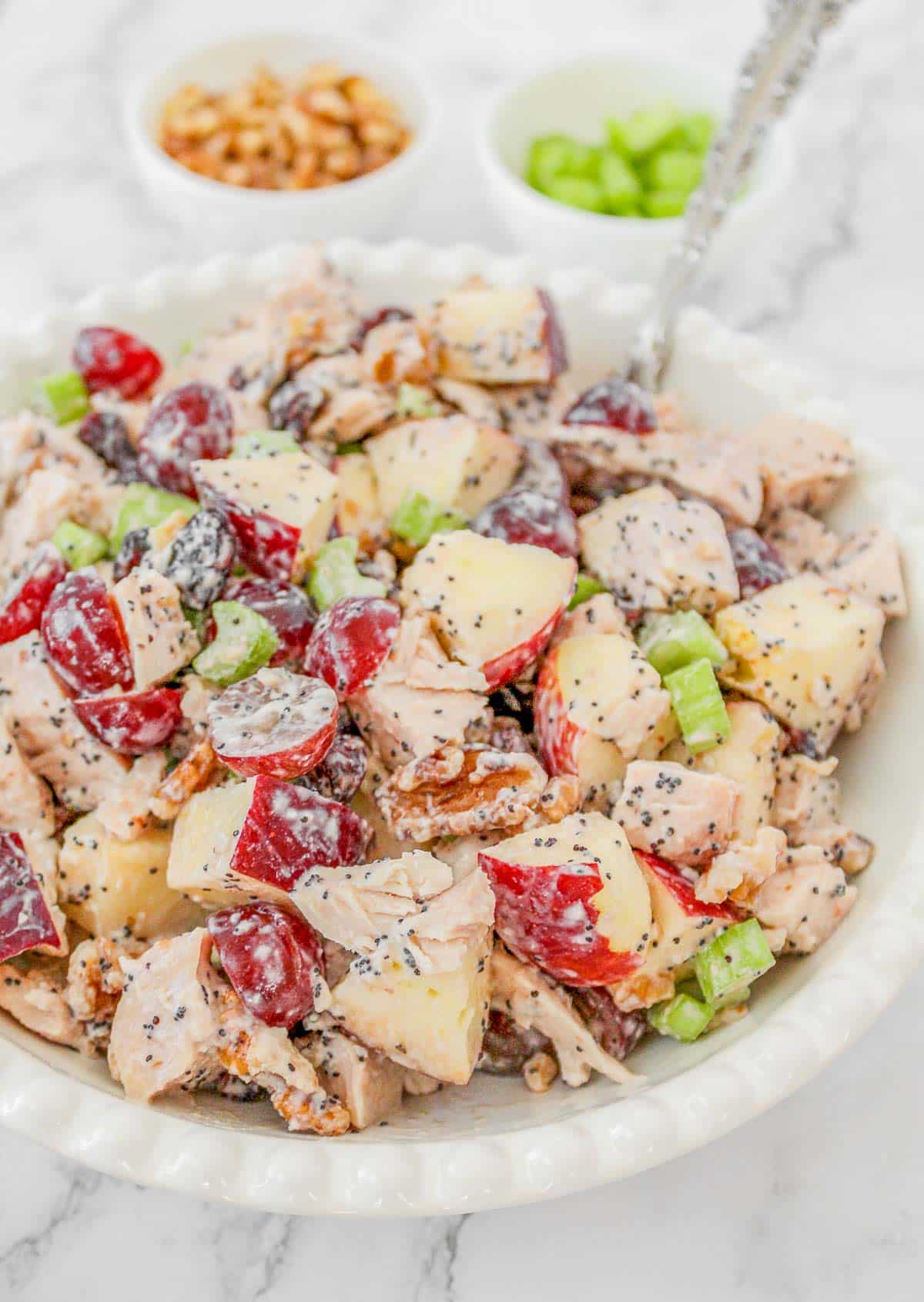 Chicken salad with grapes in a white bowl with fork inserted.