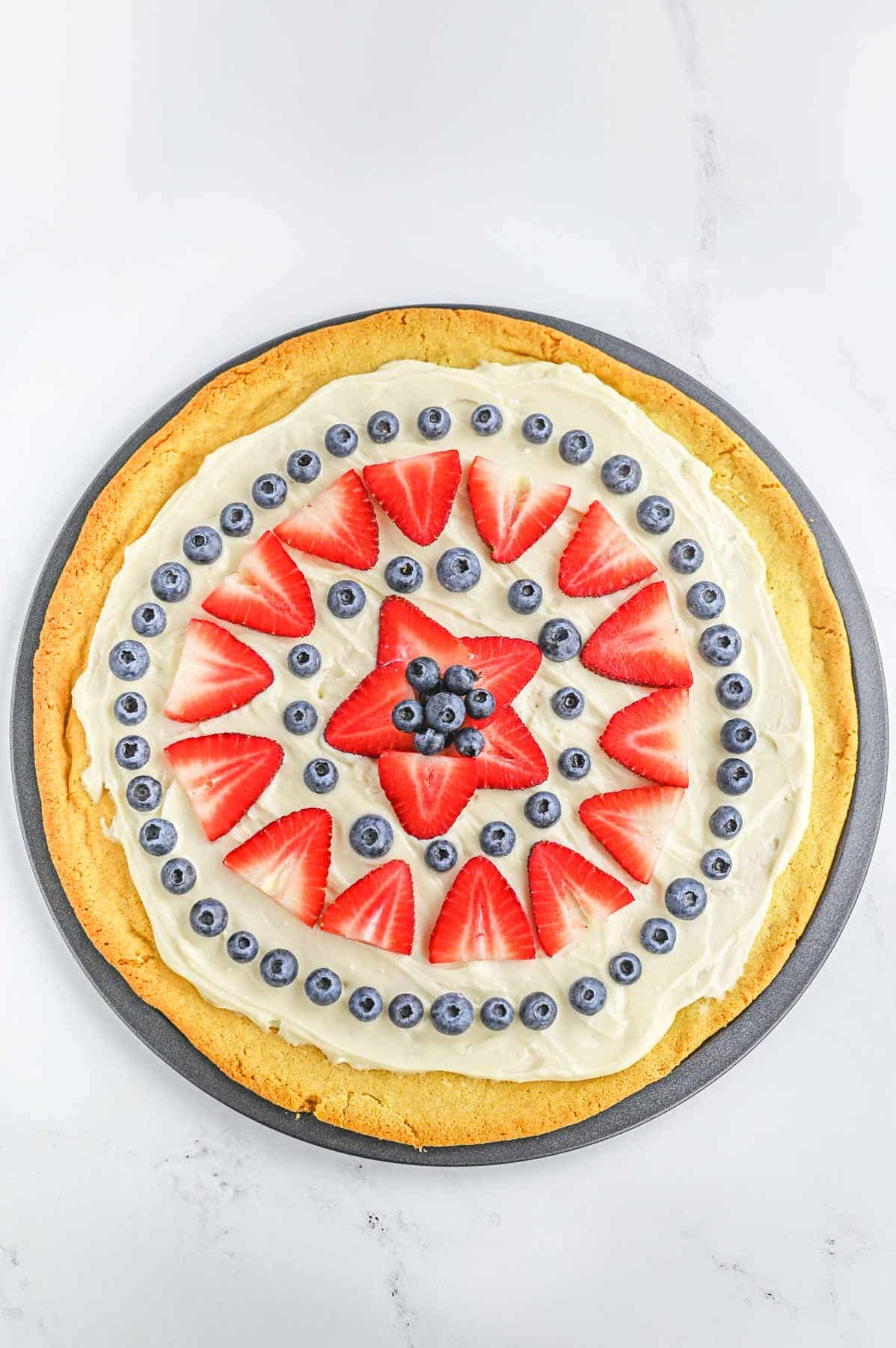 Decorated pizza with strawberries and blueberries.