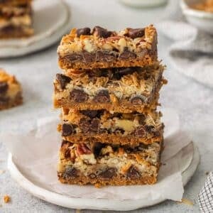 Stack of magic cookie bars on a small white plate.