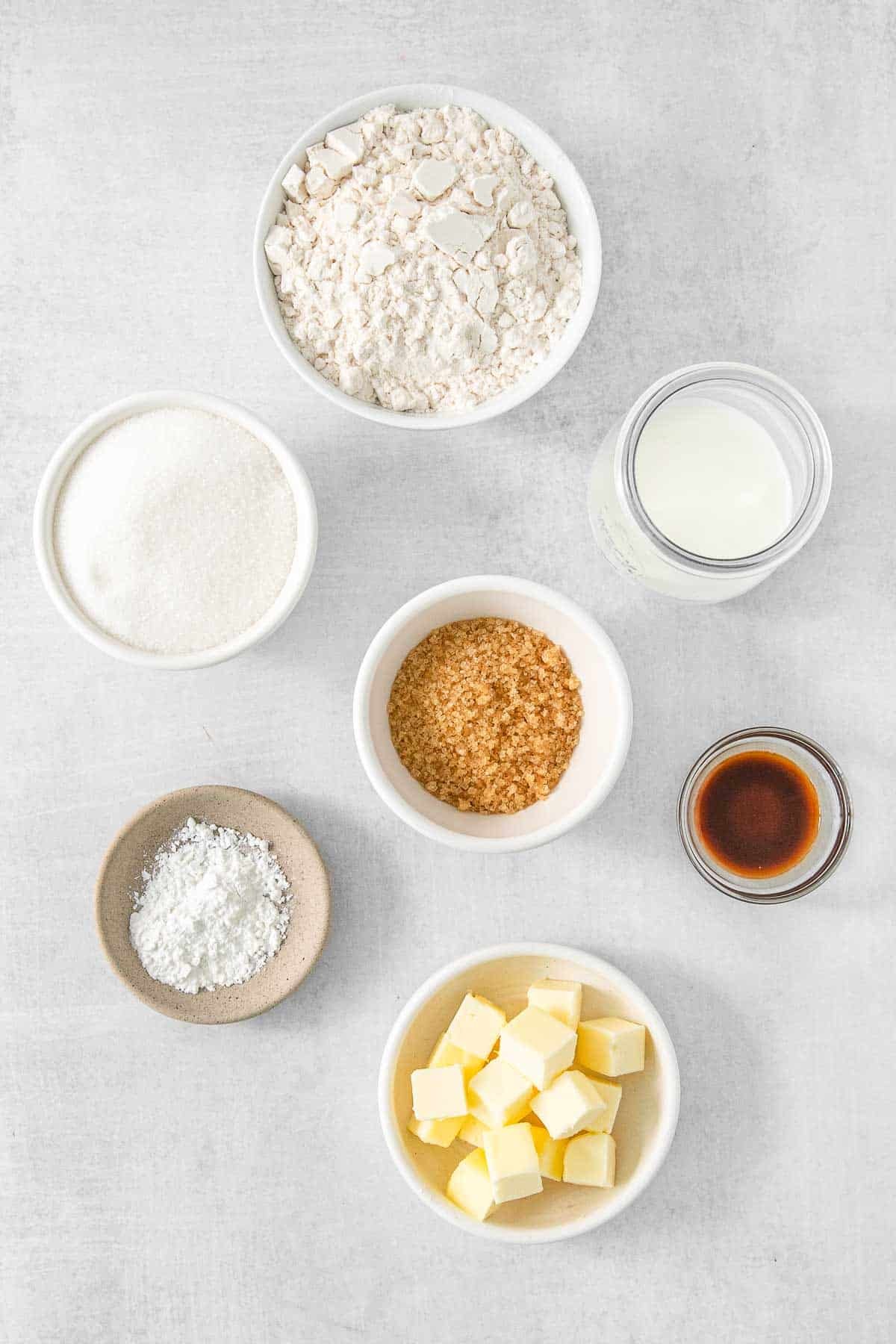Several bowls of ingredient for cobbler topping - Flour, Sugar, Baking Powder, Butter, Milk, Vanilla Extract and Turbinado.