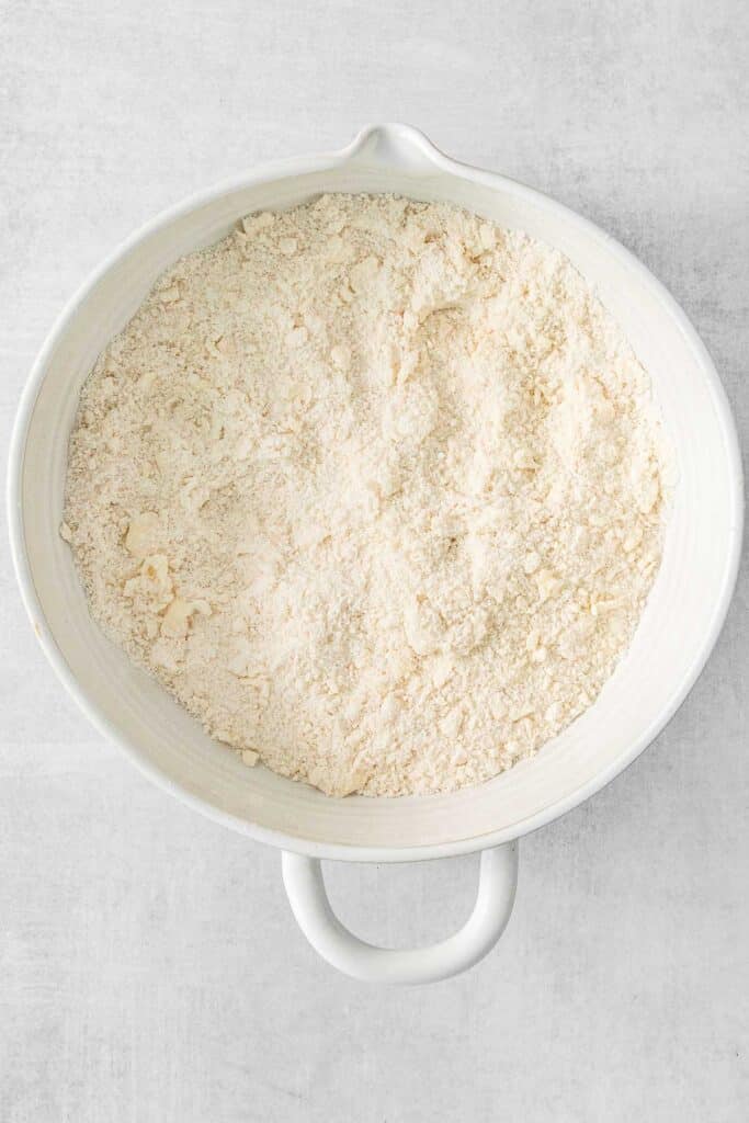 Flour, granulated sugar, and baking powder mixed together in large white mixing bowl.