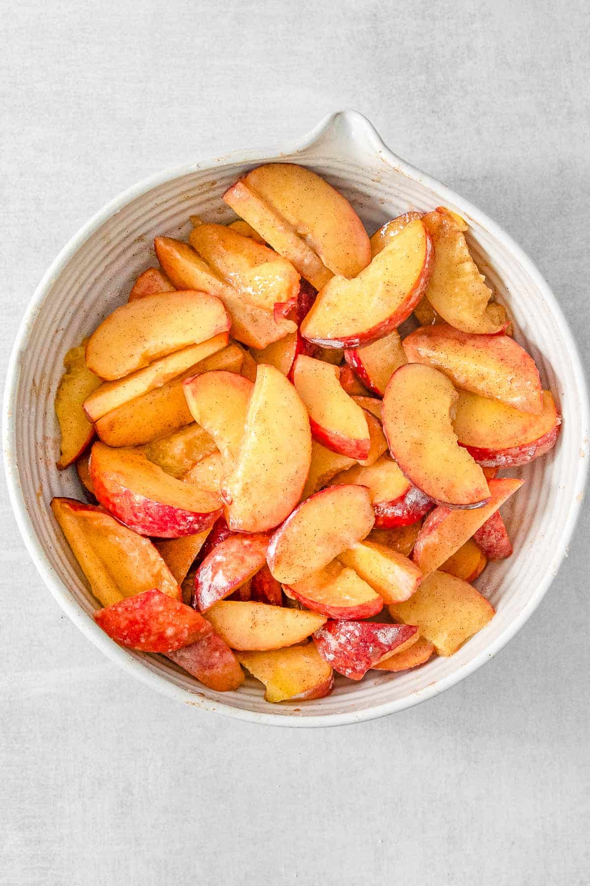 Large white bowl of sliced peaches.