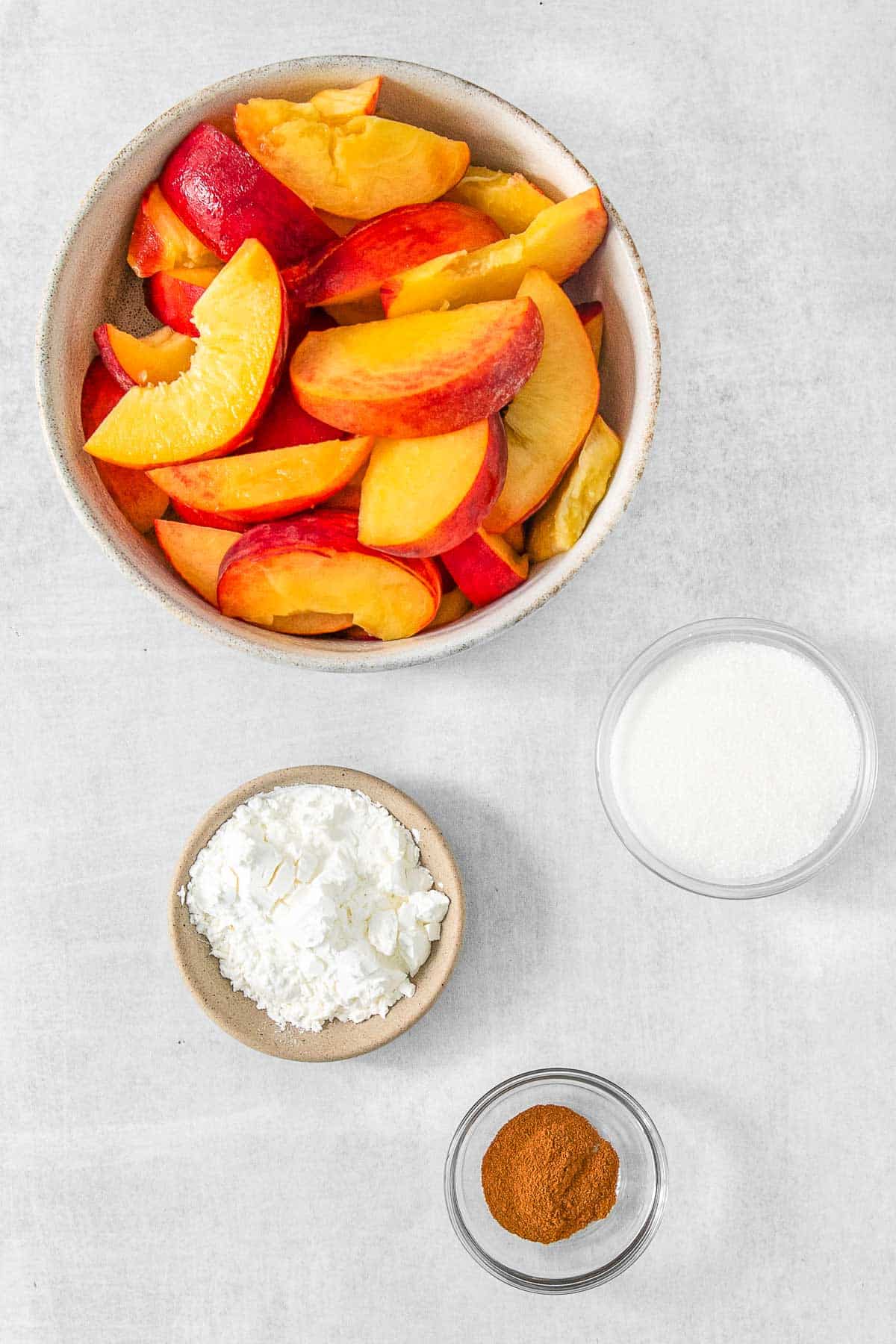 Several bowls of ingredients for Peach Cobbler - * Fresh Peaches, Granulated Sugar, Cornstarch and Ground Cinnamon.
